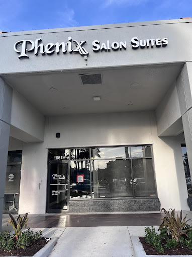 The front entrance of a salon with plants in front of it